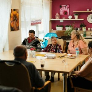Seniors enjoying a meal in a nursing home dining room with caregivers in Karviná, Czechia.